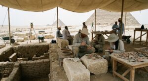 Archaeologists at a Giza-area dig inspecting stones and settlement features linked to pyramid construction work.