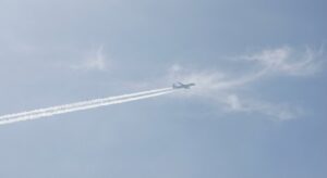 Airplane flying across a clear sky leaving long white contrails