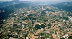 Aerial landscape showing countryside and a long circular tunnel path suggesting a large underground ring.