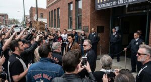 Fans gathered outside a music museum, snapping photos and watched by security staff.