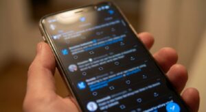 Close-up of a smartphone showing a generic social feed interface with engagement icons visible.