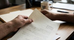 Hand holding a certified-looking paper document to suggest official records without showing readable text.