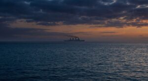 Silhouette of a large early 1900s liner at dusk, seen from the ocean surface, quiet mood.