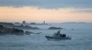 Naval training area at dawn with a vessel on patrol and a wide marine horizon.