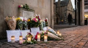 Quiet memorial with flowers and candles at an urban site, respectful and documentary in style.