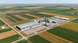 Aerial documentary shot of large-scale farmland and an industrial seed production complex under clear skies.