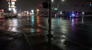Empty Las Vegas intersection at night with distant police presence, documentary atmosphere.