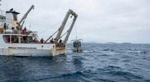 Oceanographic research vessel launching scientific instrumentation on a calm sea for environmental monitoring.