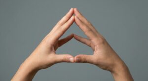 Close-up of anonymous hands forming a triangle shape against a neutral backdrop, no branding.